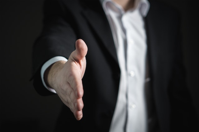 person in a suit reaching out their hand for a handshake