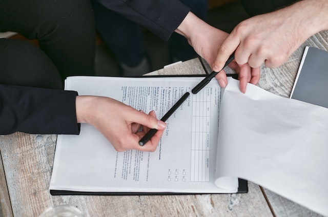 Hand holding a pen and reviewing a form on a clipboard