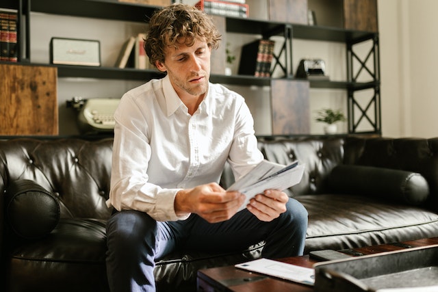 Person sitting on a couch and looking through a pile of envelopes